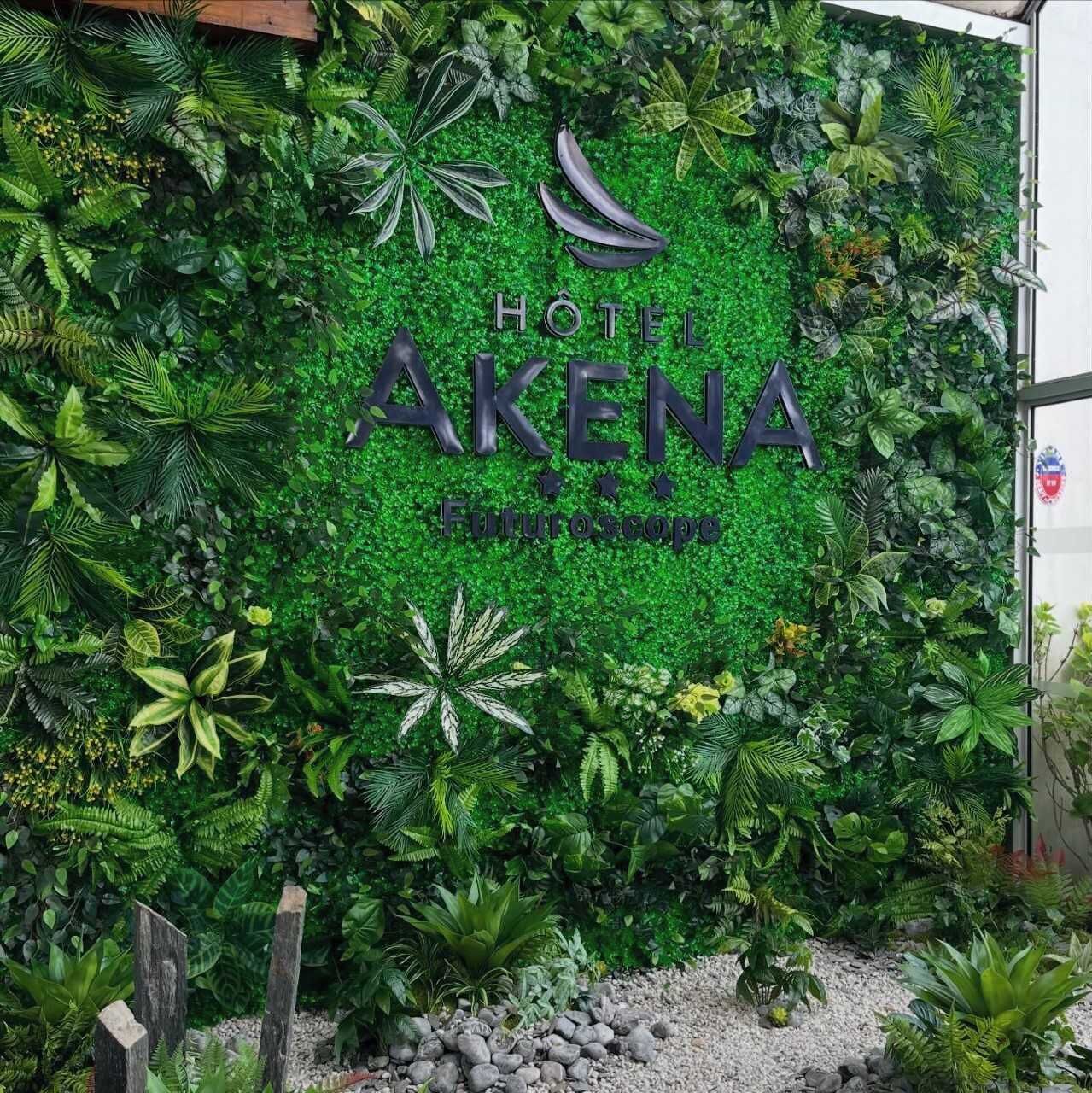 A hotel sign with 'HOTEL AKENA' and 'FuturoScope' written on a green leafy wall.