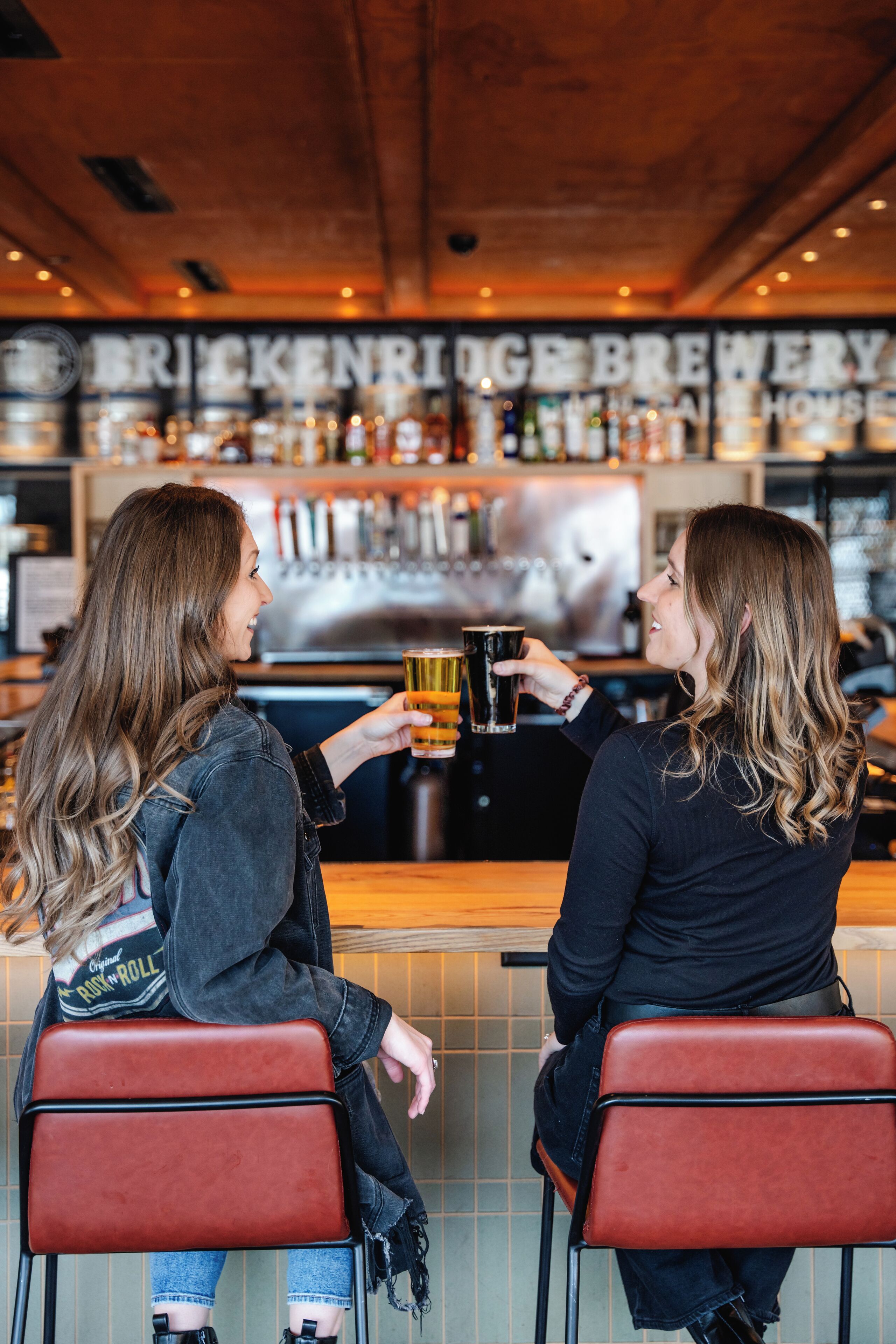 Dos personas sentadas en un bar, con un letrero que dice "BRICKENRIGE BREWERY" al fondo.