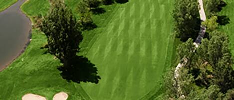 Luchtbeeld van een golfbaan met zandbunkers, waterhindernissen en een clubhuis.