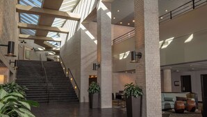 A spacious lobby with a high ceiling, a staircase, and a seating area with a sofa and coffee table.