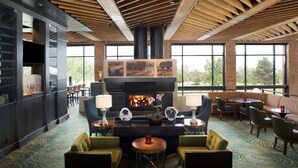 A spacious lounge area with a fireplace, comfortable seating, and large windows offering a view of the outdoors.