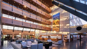 A spacious lobby with multiple seating areas, a reception desk, and a large mural on the wall.