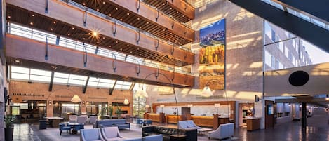 A spacious lobby with multiple seating areas, a reception desk, and a large mural on the wall.