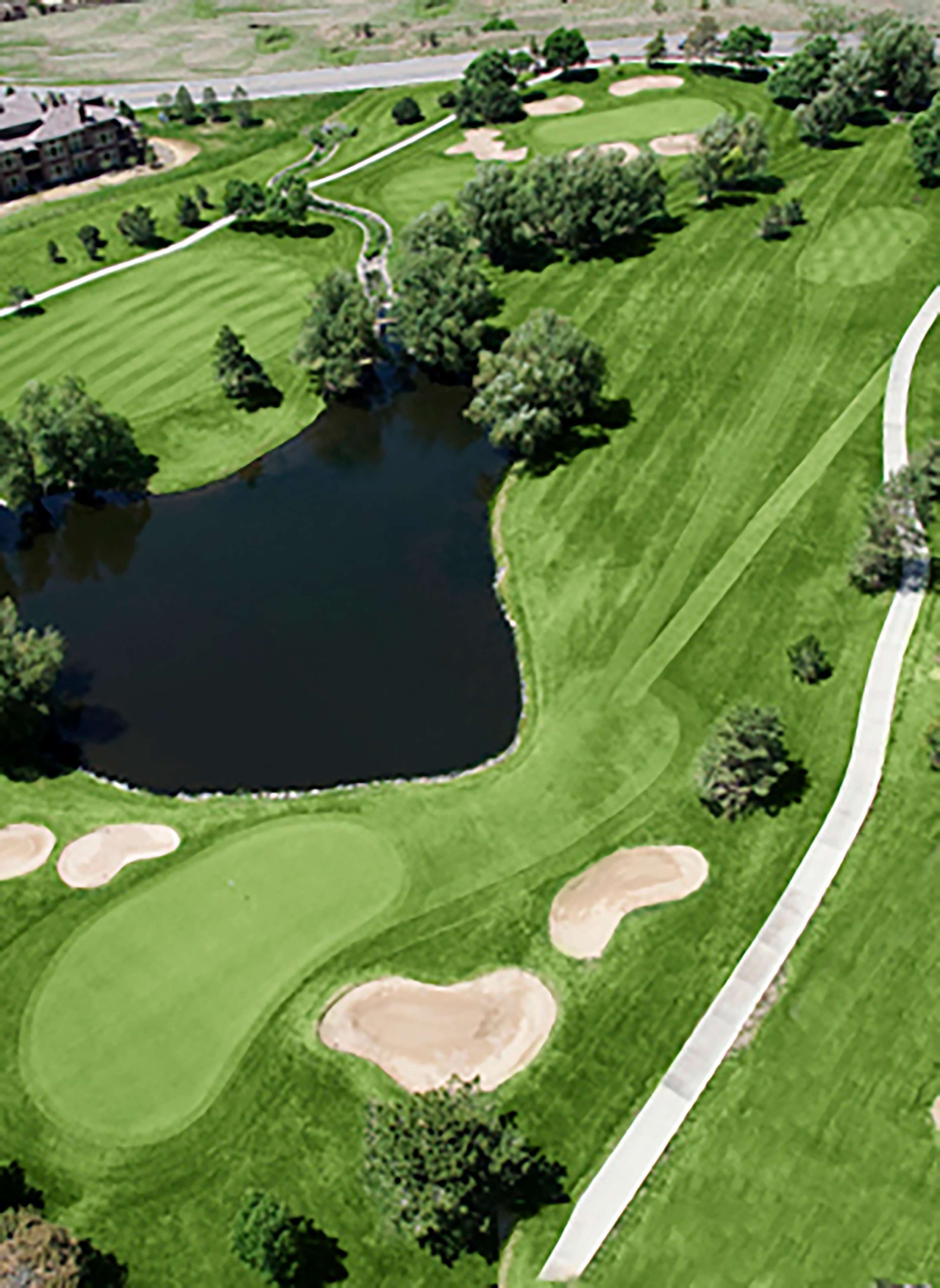 An aerial view of a golf course with a pond, sand bunkers, and a clubhouse.