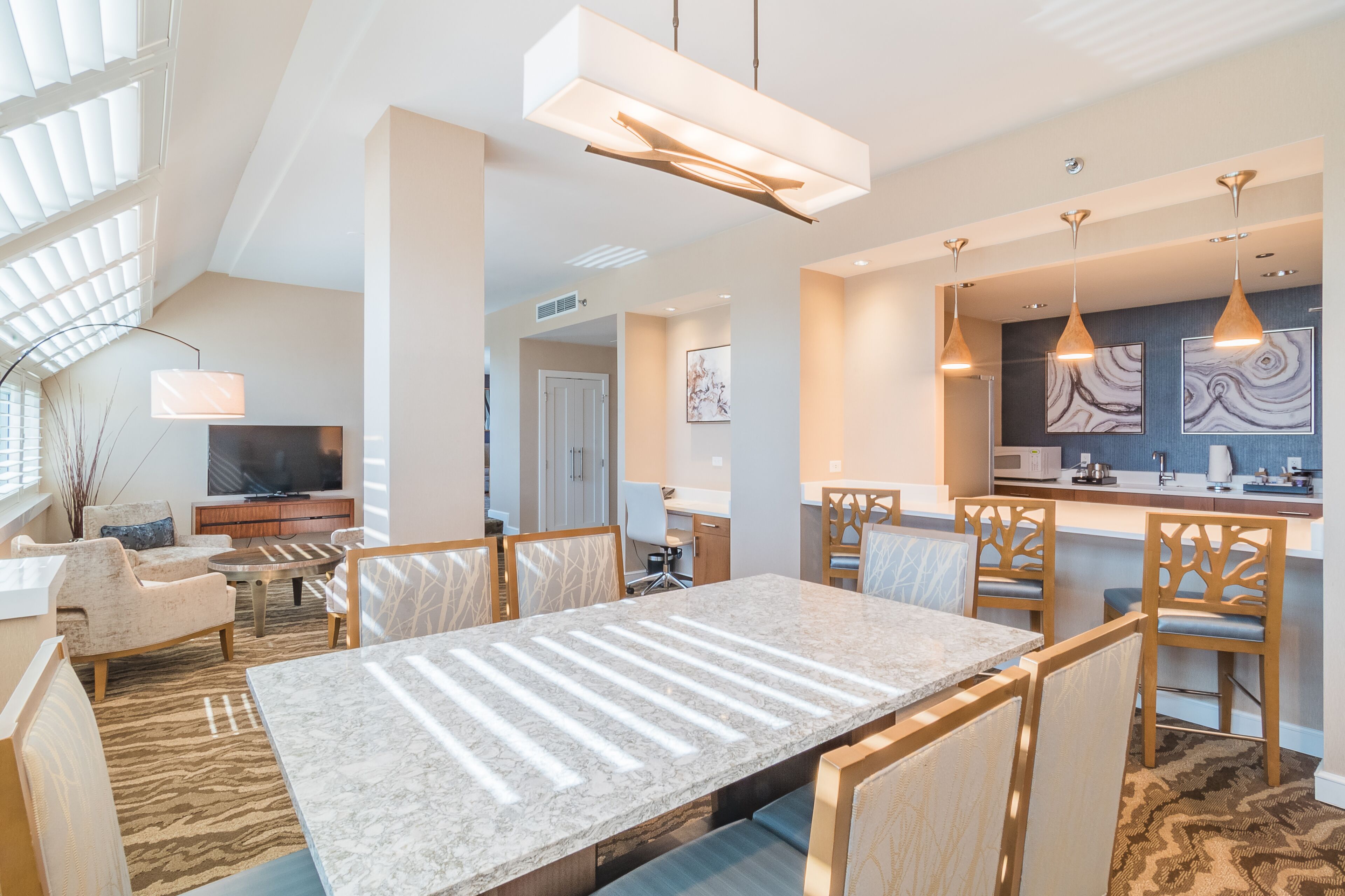 Una sala de estar moderna con una gran mesa de comedor, asientos cómodos y una zona de cocina con barra.