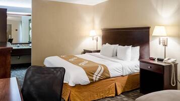 A hotel room with a large bed, two bedside tables, a desk, and a chair.