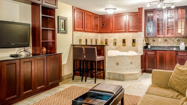 A modern kitchen with wooden cabinets, a built-in island, and a flat-screen TV. - Quality Inn Moss Point - Pascagoula (Moss Point)