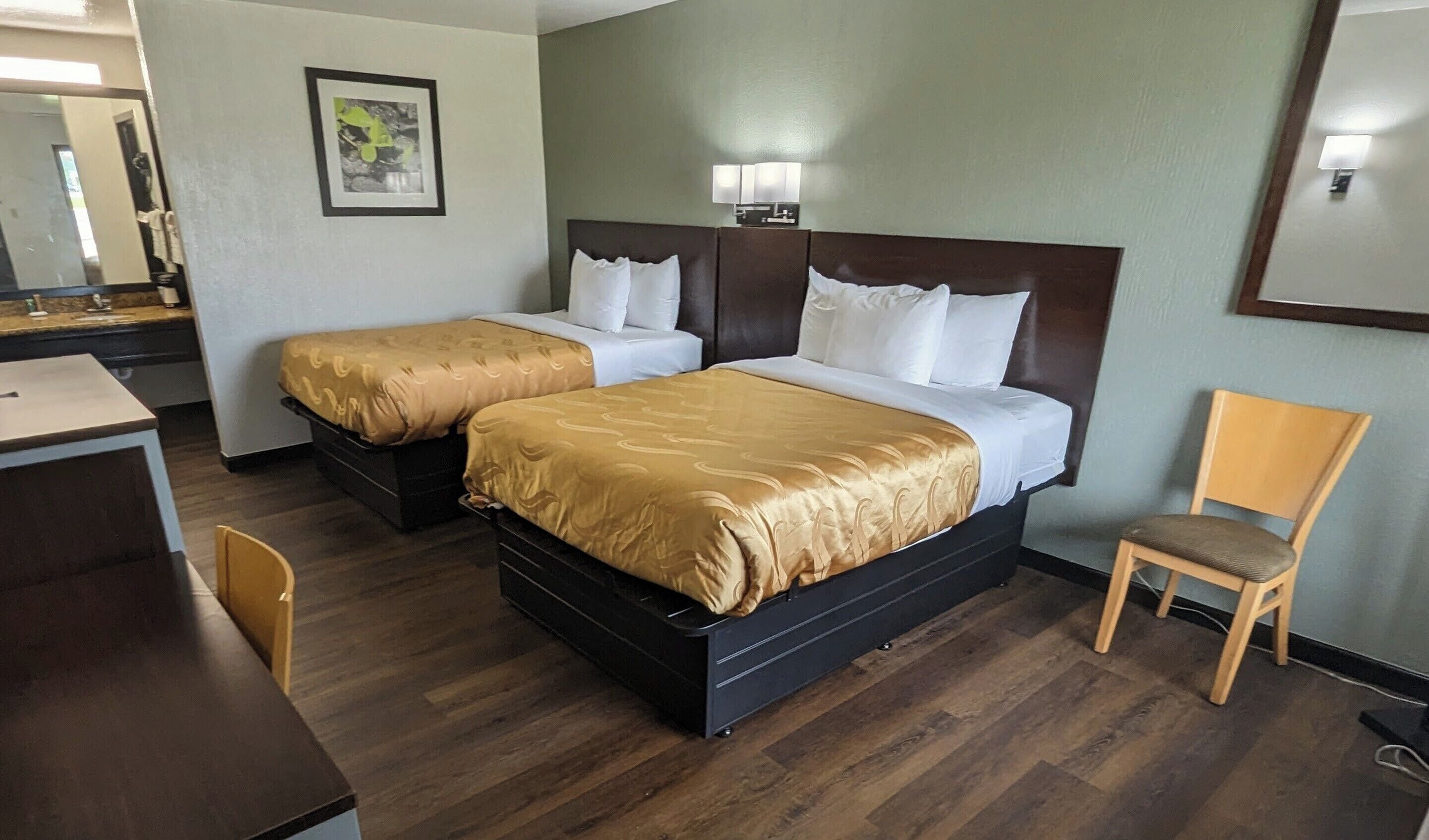 Een hotelkamer met twee bedden, een bureau en een stoel.