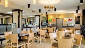 A restaurant with round tables and chairs, a popcorn machine, and a counter with a menu. - Quality Inn Moss Point - Pascagoula (Moss Point)