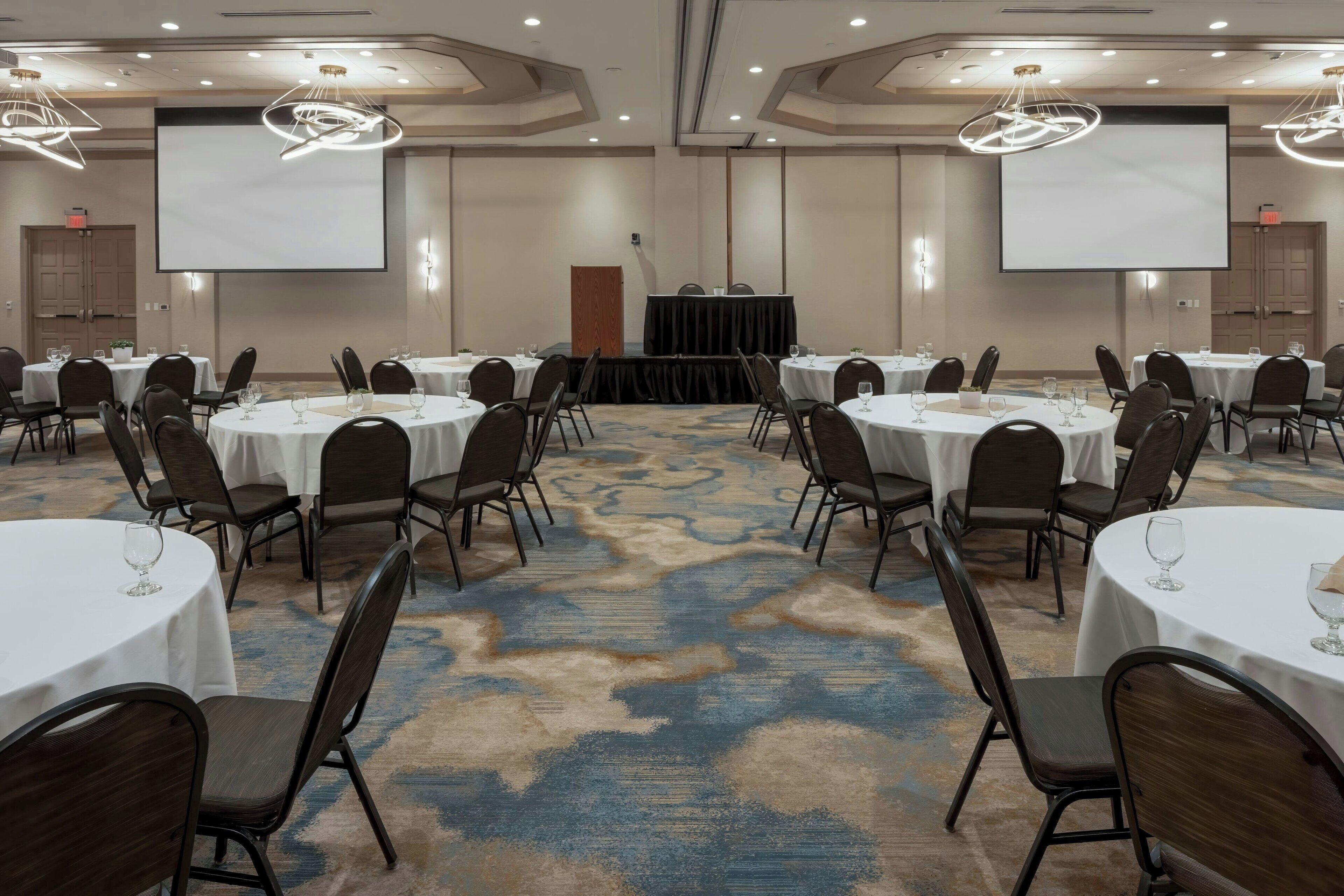 A conference room with round tables, chairs, and a podium.