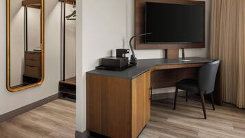 Une chambre d’hôtel moderne avec un bureau en bois, un téléviseur à écran plat, un miroir et une chaise.