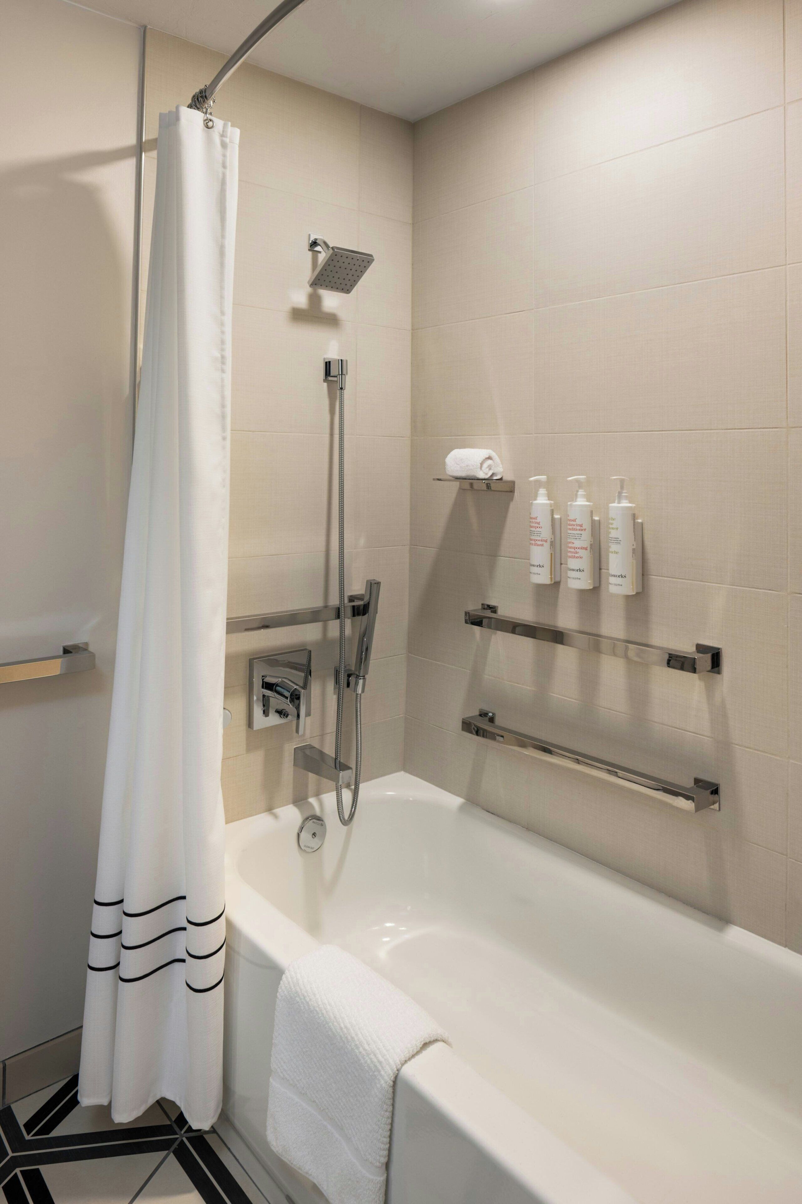 Ein modernes Badezimmer mit Badewanne, Dusche und Handtuchhalter.