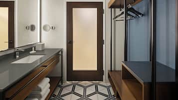 A modern bathroom with a double sink vanity, a mirror, a towel rack, and a shower area.