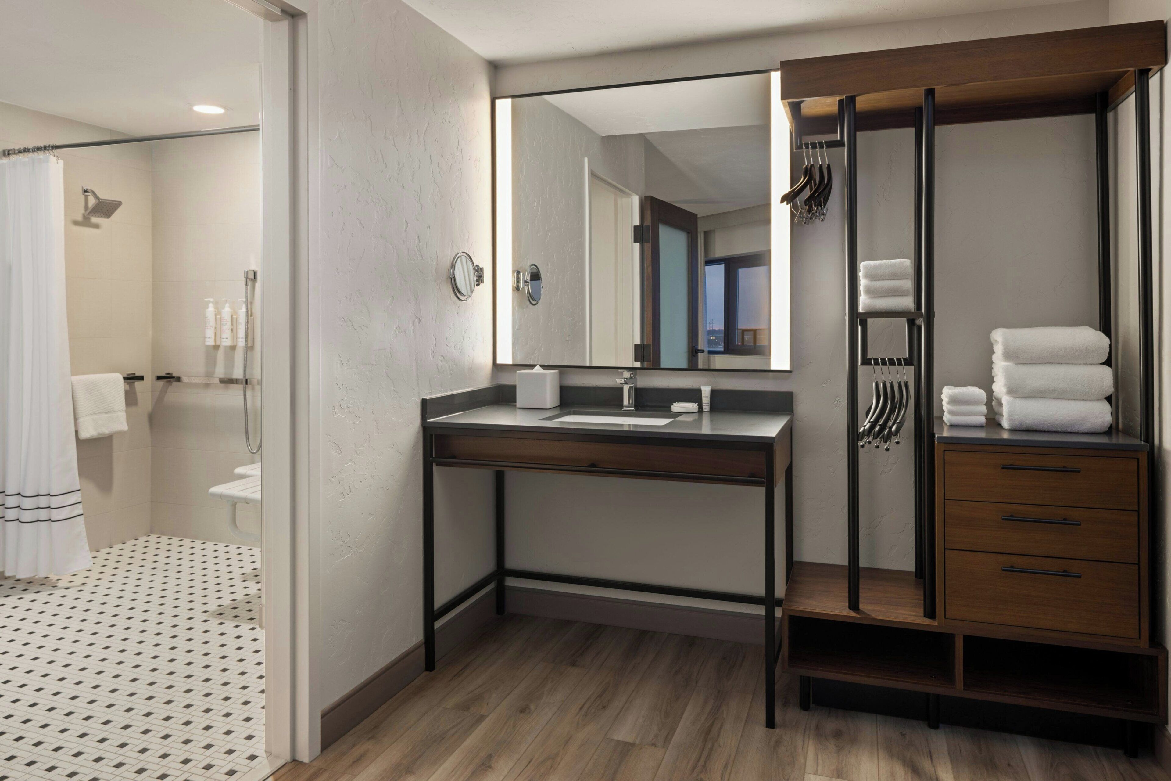 Un baño moderno con ducha, lavamanos, espejo y tocador de madera.