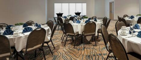 A conference room with multiple tables set for dining, equipped with chairs, tables, and centerpieces.