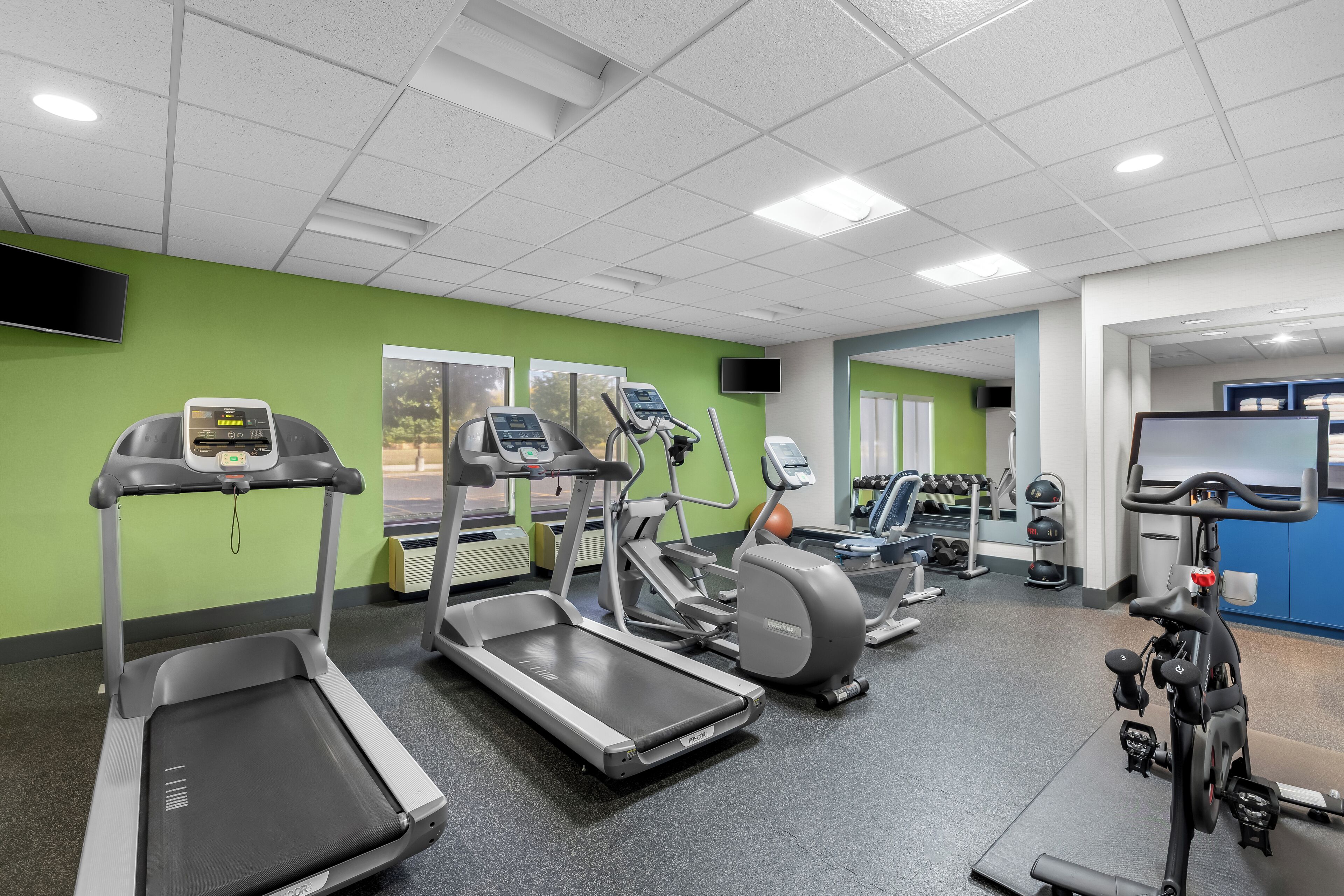 Ein Fitnessstudio mit Laufbändern, Crosstrainern und Ergometer.