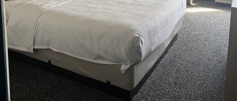 Hotellihuone, jossa on suuri sänky, tuoli, työpöytä ja ovi, joka johtaa kylpyhuoneeseen.