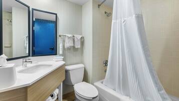 A modern bathroom with a white sink, toilet, and bathtub. There is a shower curtain, a towel rack with towels, and a mirror above the sink.