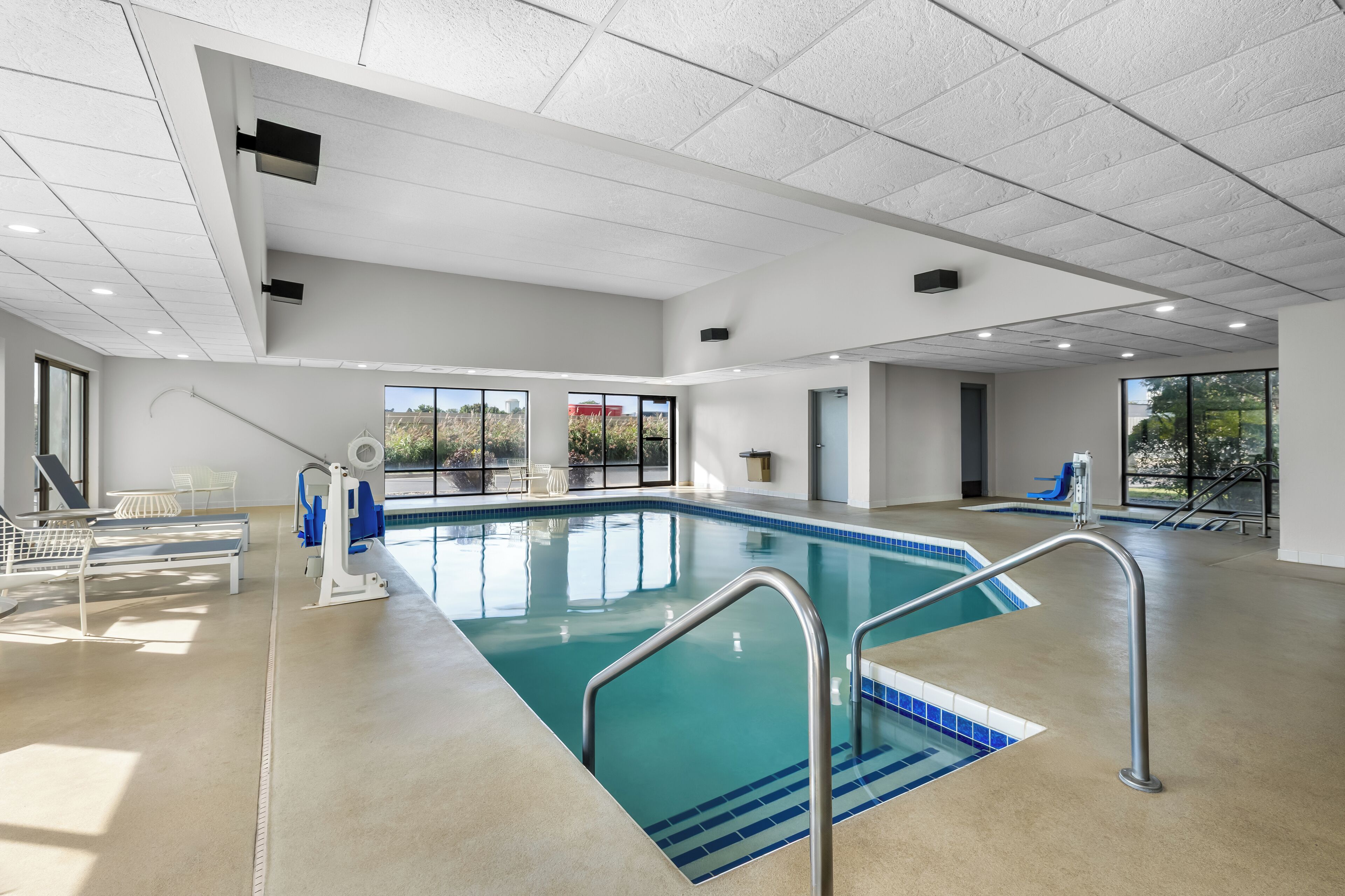 A large indoor swimming pool with clear blue water, surrounded by white walls and a high ceiling.