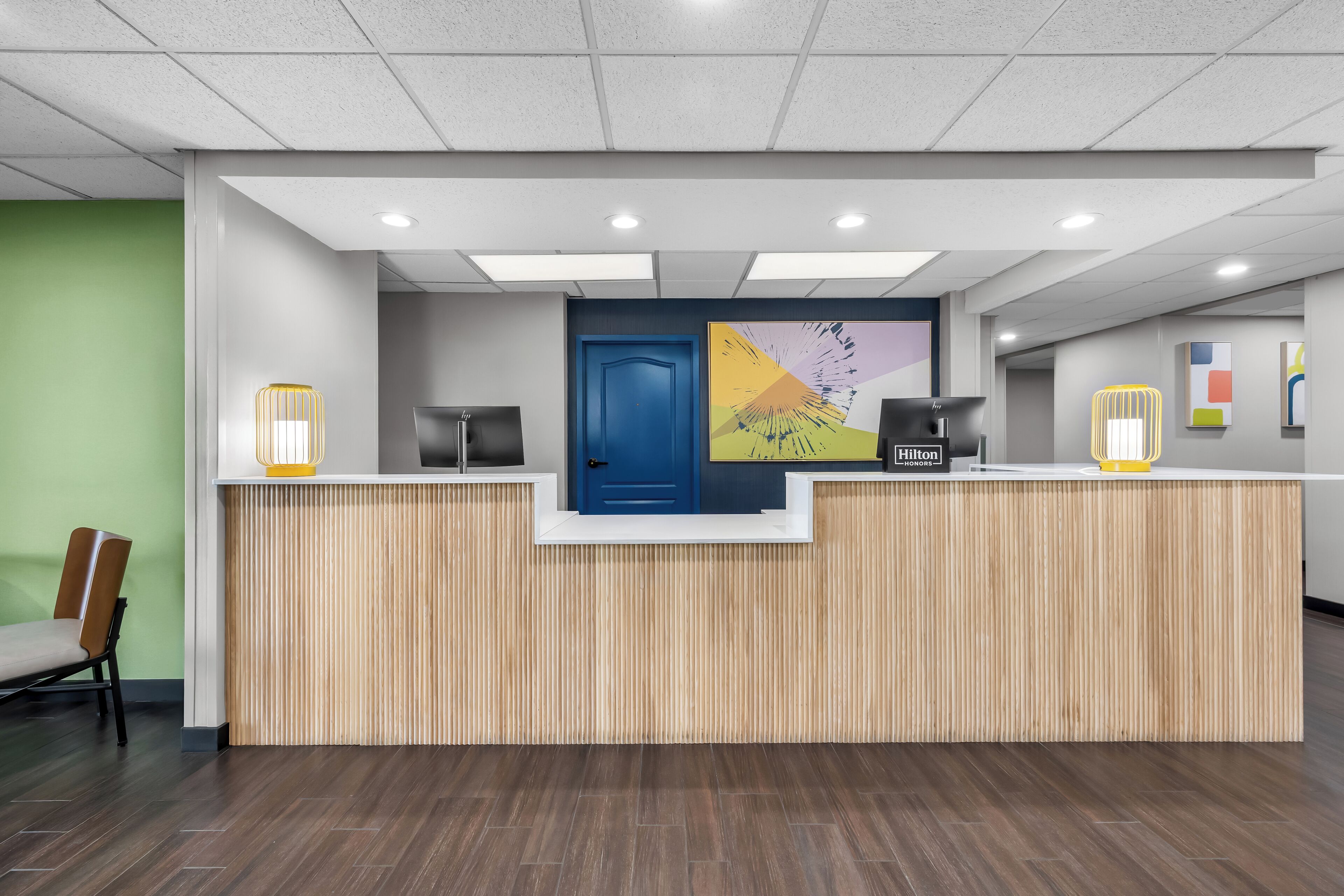 A reception desk with a blue door, a large abstract artwork, and a "Hilton Honors" sign.