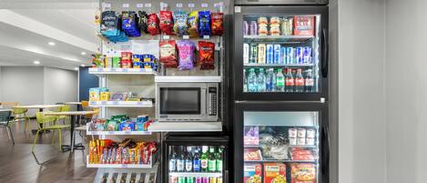 Een automaatgedeelte met magnetrons, schappen vol snacks en drankautomaten.