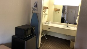 A compact hotel room with a kitchenette, including a microwave and iron, a sink, and a large mirror. - Jax Inn (Jacksonville)
