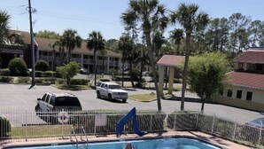 A rectangular swimming pool with a surrounding fence, lounge chairs, and an umbrella. - Jax Inn (Jacksonville)