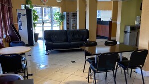 A restaurant with a black leather couch, a dining table with chairs, and hanging pendant lights. - Jax Inn (Jacksonville)