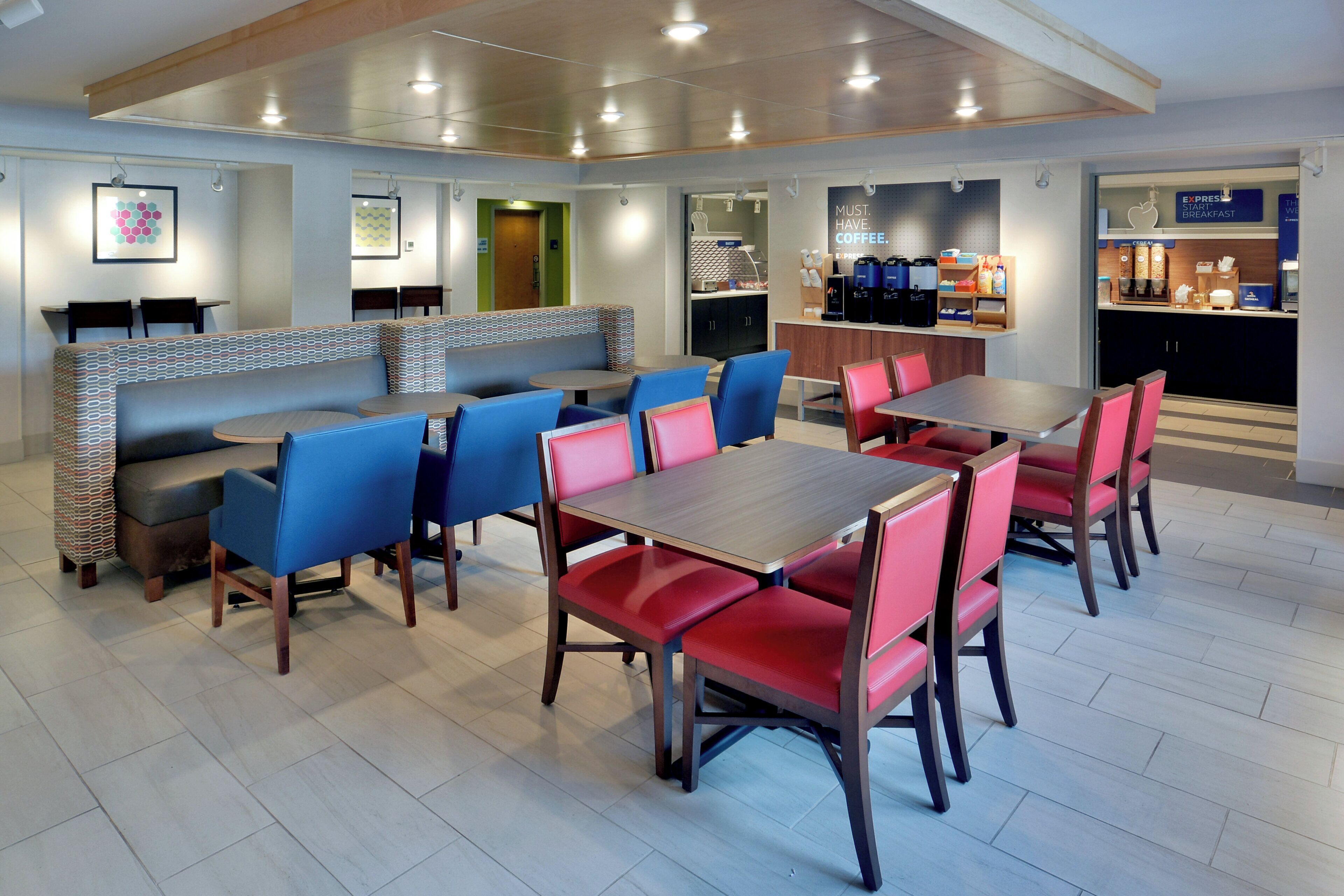 A modern dining area with booths and tables, a coffee station, and a counter with breakfast items.