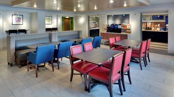 A modern dining area with booths and tables, a coffee station, and a counter with breakfast items.