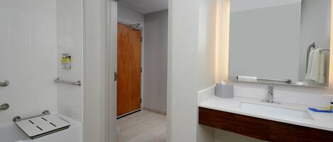Une salle de bain moderne avec un lavabo blanc, un meuble-lavabo en bois, un miroir et un espace douche.