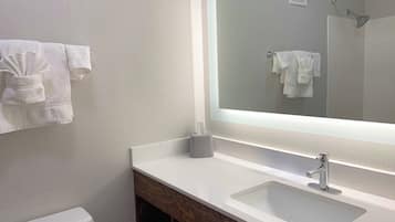 A bathroom with a white sink, a large mirror, and a towel rack with folded towels.