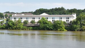 A white building with a flat roof, located beside a body of water with trees in the foreground. - Holiday Inn Express Danville by IHG (Danville)