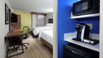 Une chambre d’hôtel équipée d’un bureau, d’une chaise, d’un lit et d’un mini-bar avec une machine à café.