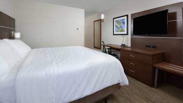 Une chambre d’hôtel avec un grand lit, un bureau, un téléviseur à écran plat fixé au mur et un miroir.