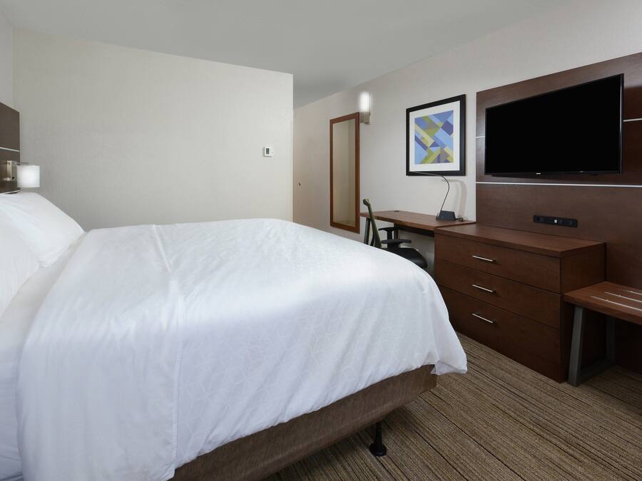 Une chambre d’hôtel avec un grand lit, un bureau, un téléviseur à écran plat fixé au mur et un miroir.
