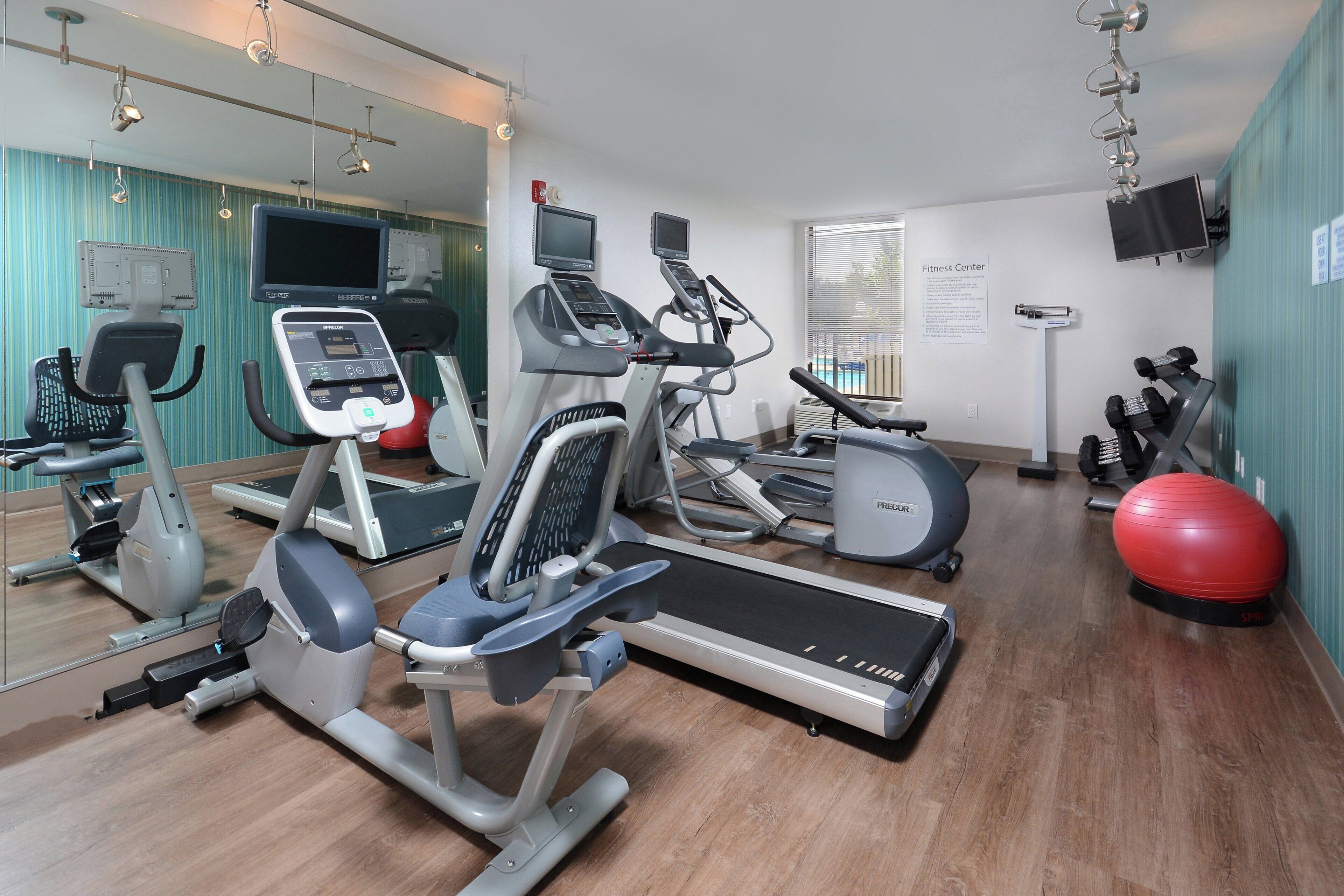Un gimnasio con máquinas de cardio, una cinta de correr y pelotas de ejercicio.