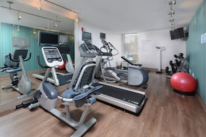 Centro de atividades físicas com máquinas de cardio, esteira e bolas de exercícios.