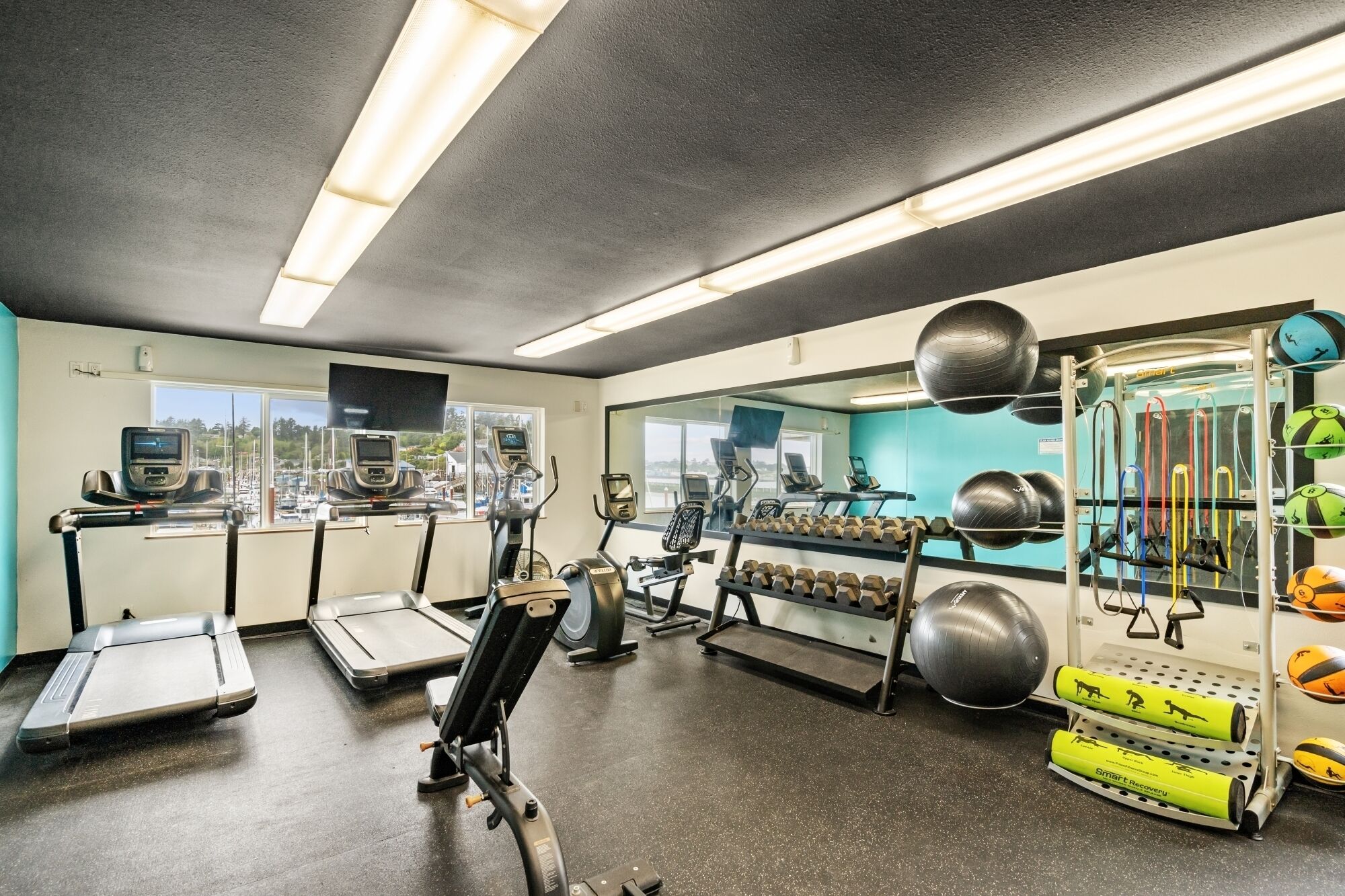 Un gimnasio con cintas de correr, elípticas y diversos equipos de ejercicio.