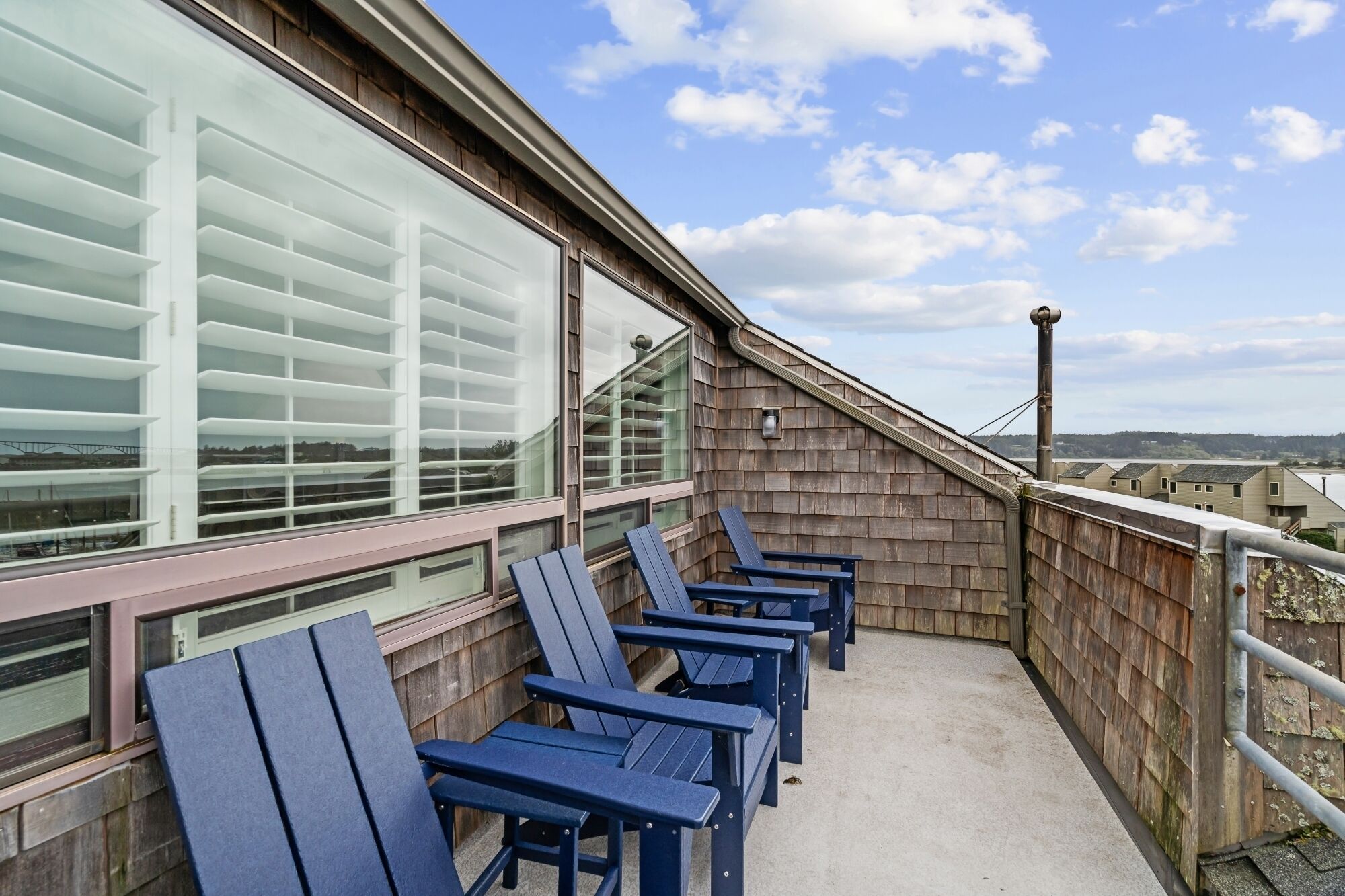 A balcony with blue chairs and a view of the cityscape.