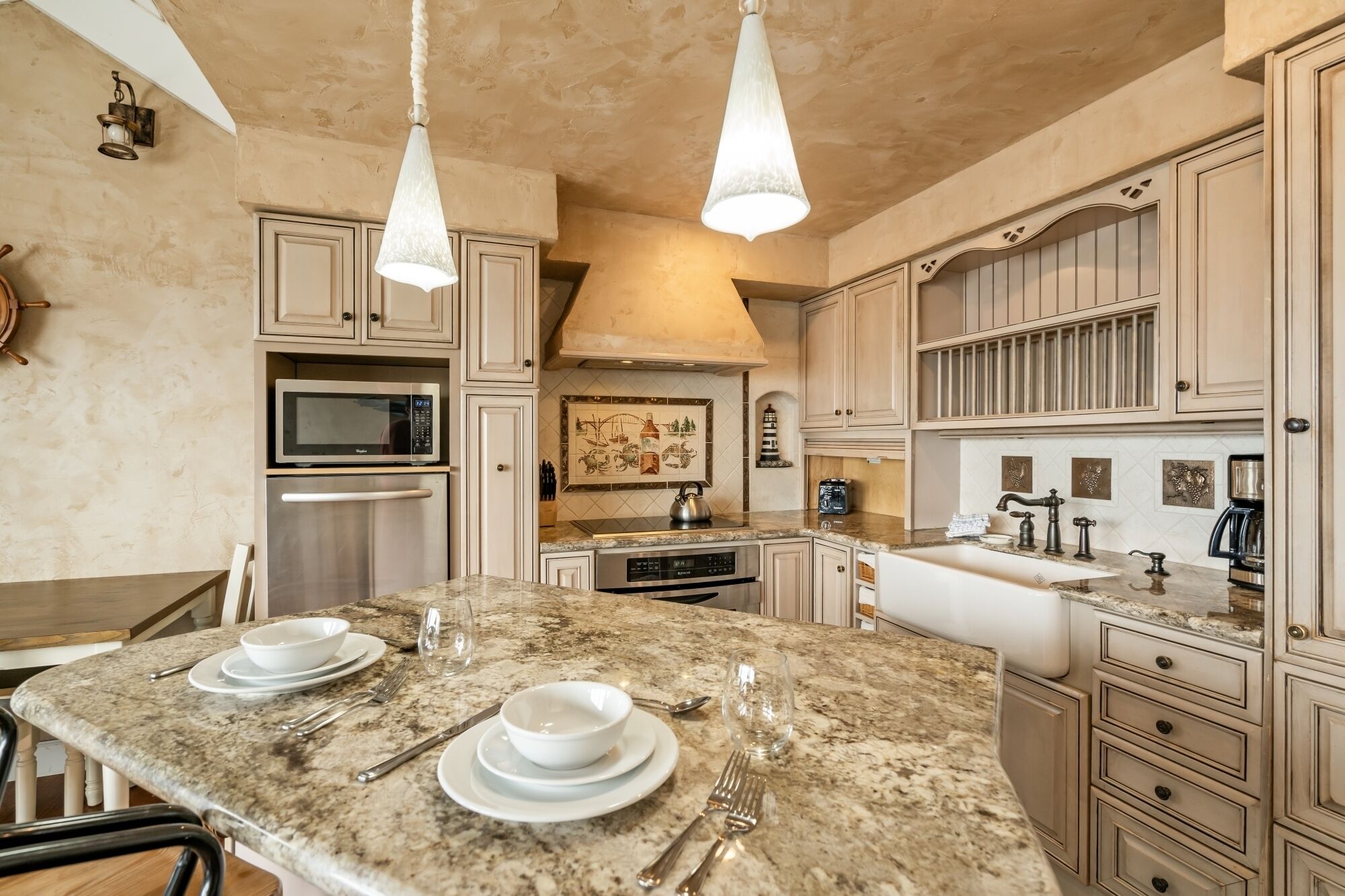 A kitchen with a granite countertop, stainless steel appliances, and a dining area with a table set for four.