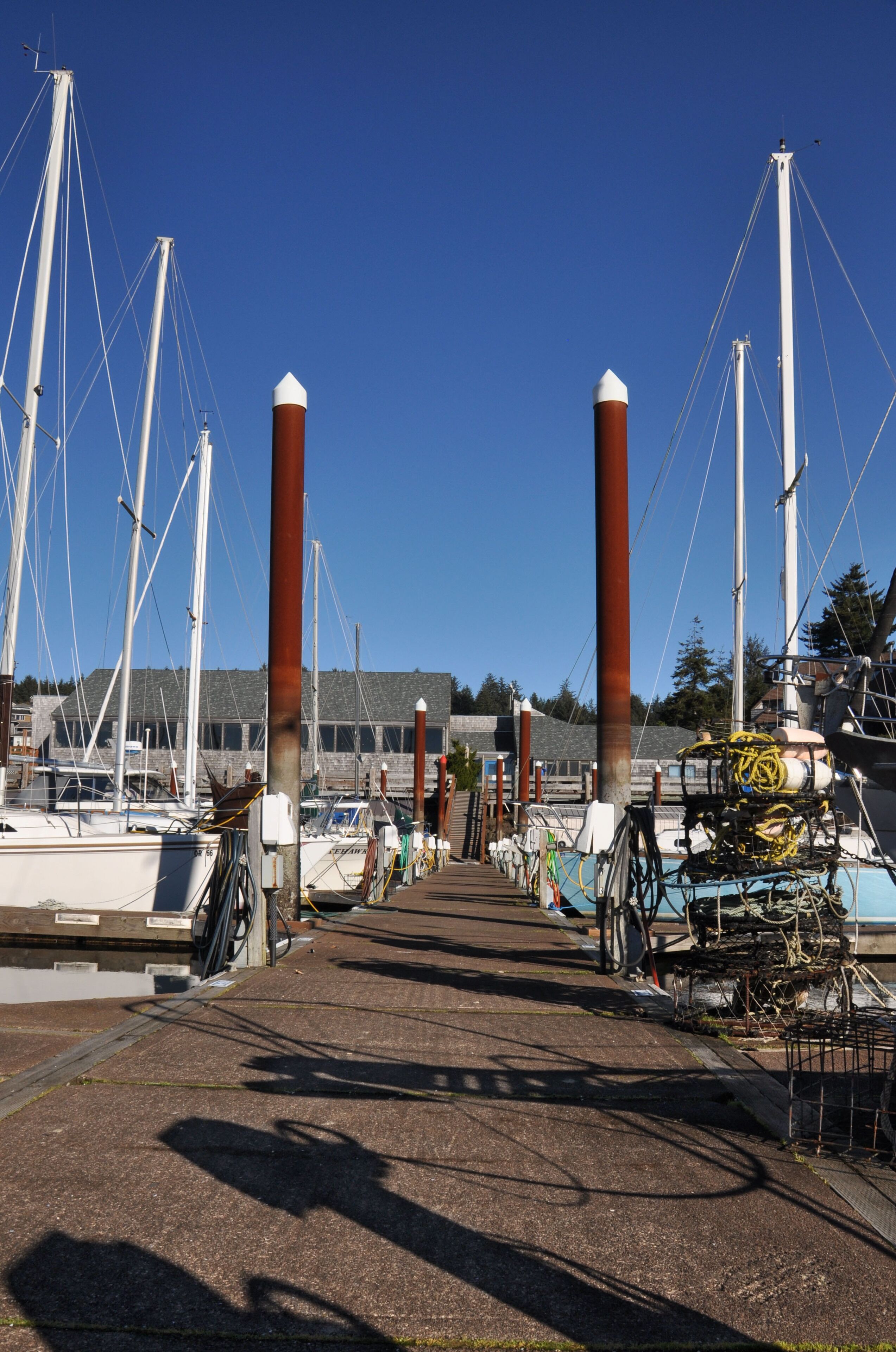 A marina with boats docked, a clear sky, and a building in the background.