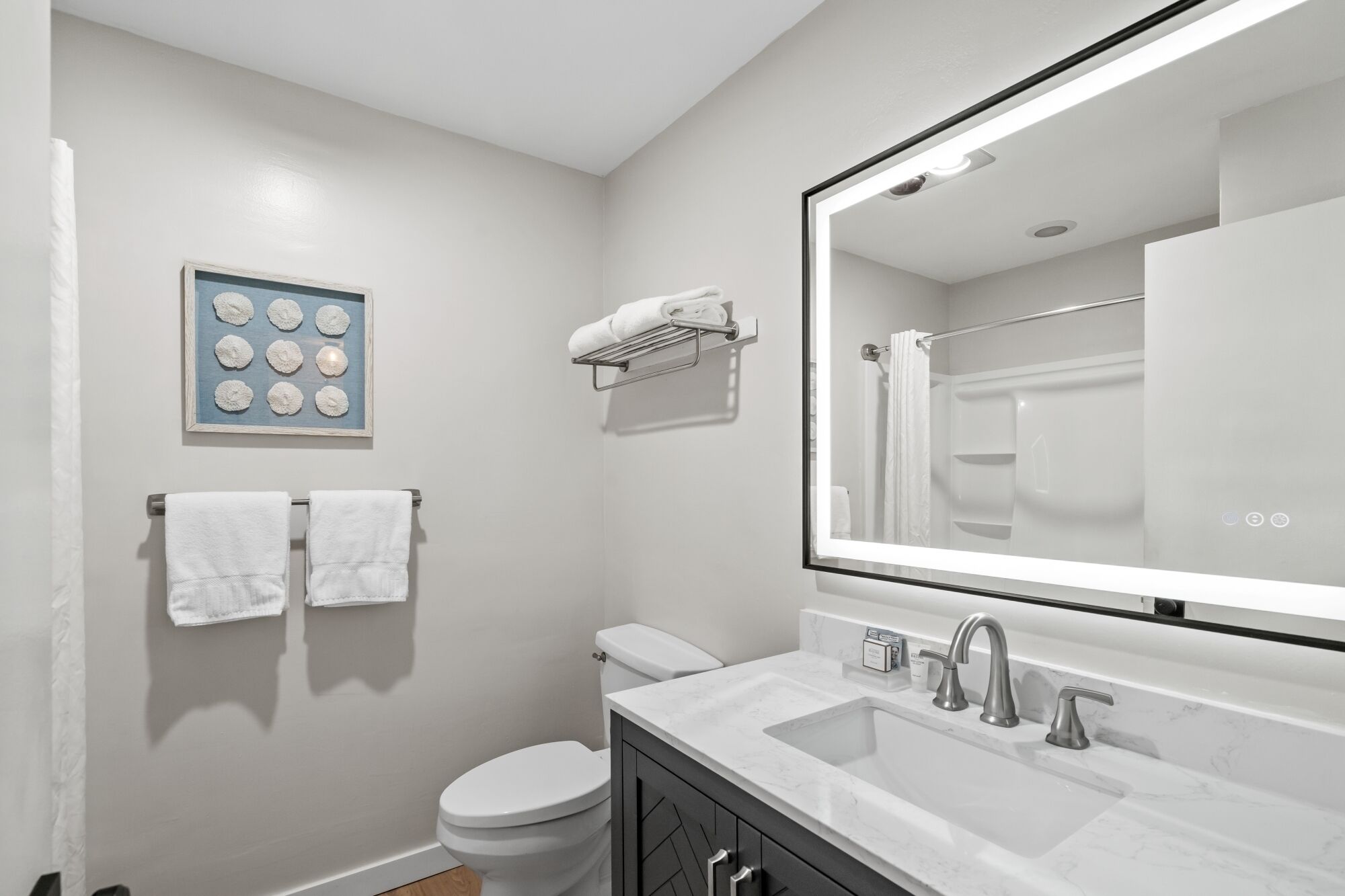 A modern bathroom with a toilet, sink, and mirror.