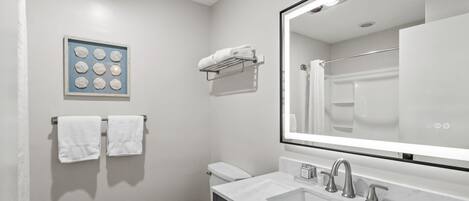 A modern bathroom with a toilet, sink, and mirror.