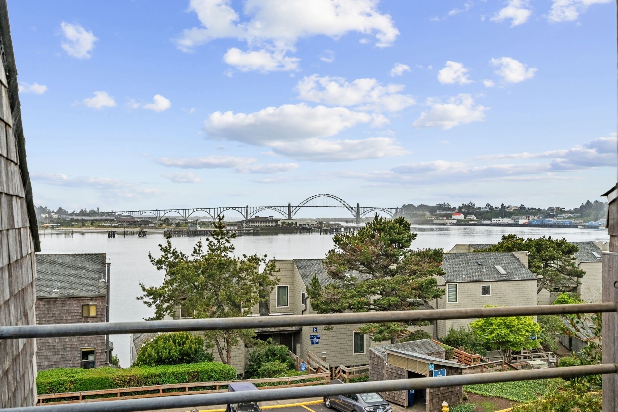 A view of a river with a bridge, buildings, and a parking area.