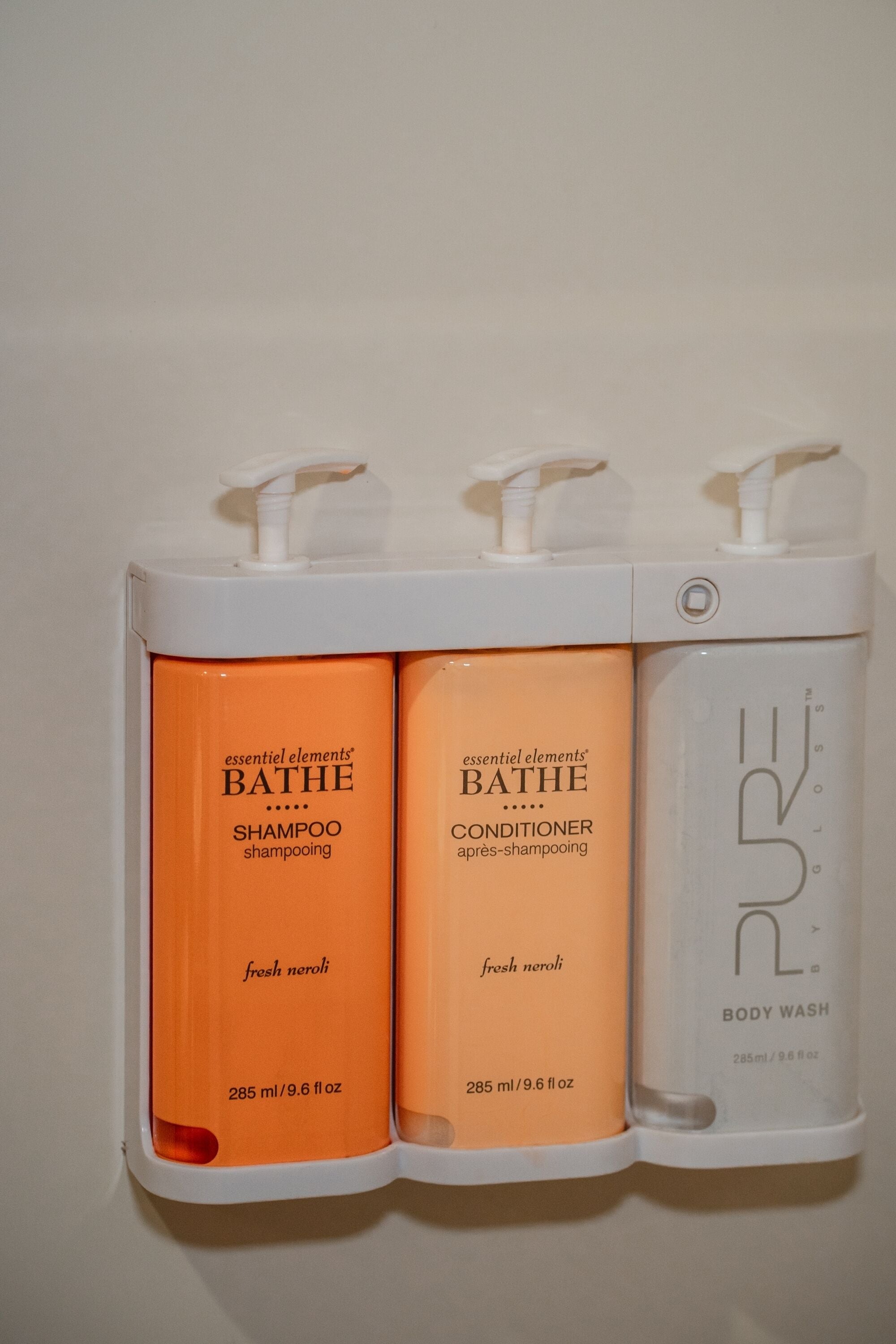 Three bottles of essential elements bath products: shampoo, conditioner, and body wash.