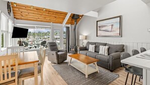 A modern living room with a wooden ceiling, a sofa set, a coffee table, and a TV. - Embarcadero Resort Hotel & Marina (Newport)