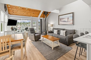 A modern living room with a wooden ceiling, a sofa set, a coffee table, and a TV. - Embarcadero Resort Hotel & Marina (Newport)