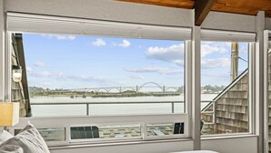 A bedroom with a large window overlooking a river and a bridge. - Embarcadero Resort Hotel & Marina (Newport)