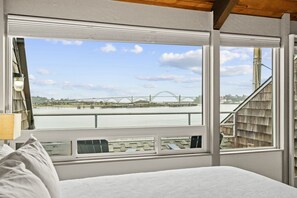 A bedroom with a large window overlooking a river and a bridge. - Embarcadero Resort Hotel & Marina (Newport)
